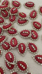 Red oval stones with gold and clear gemstone accents on a textured beige background