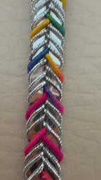 Multicolored braided cable held between fingers against a beige background