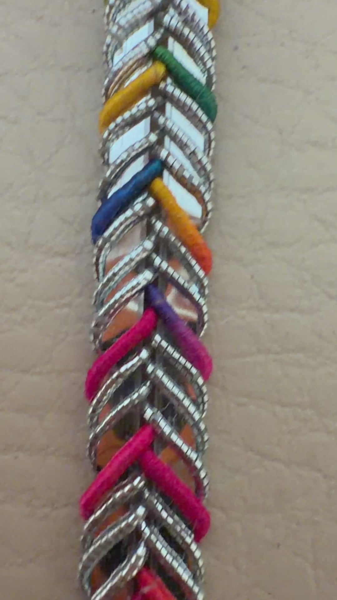 Multicolored braided cable held between fingers against a beige background