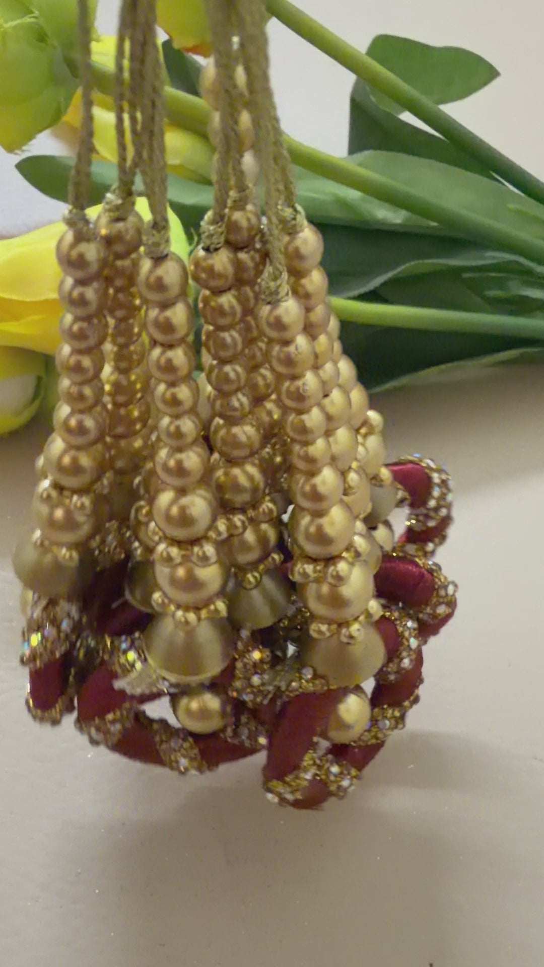 Decorative earrings with gold and red details on a light background with flowers.