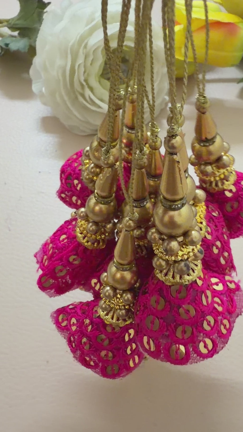 Pair of pink tassel earrings with gold accents on a light gray background