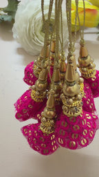 Pair of pink tassel earrings with gold accents on a light gray background