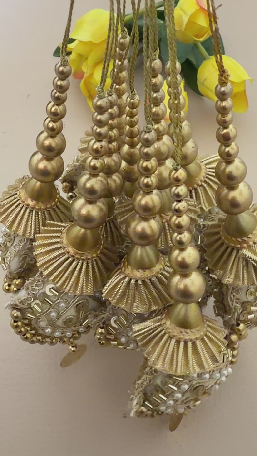 Decorative gold and pearl pendant next to a ruler on a beige background