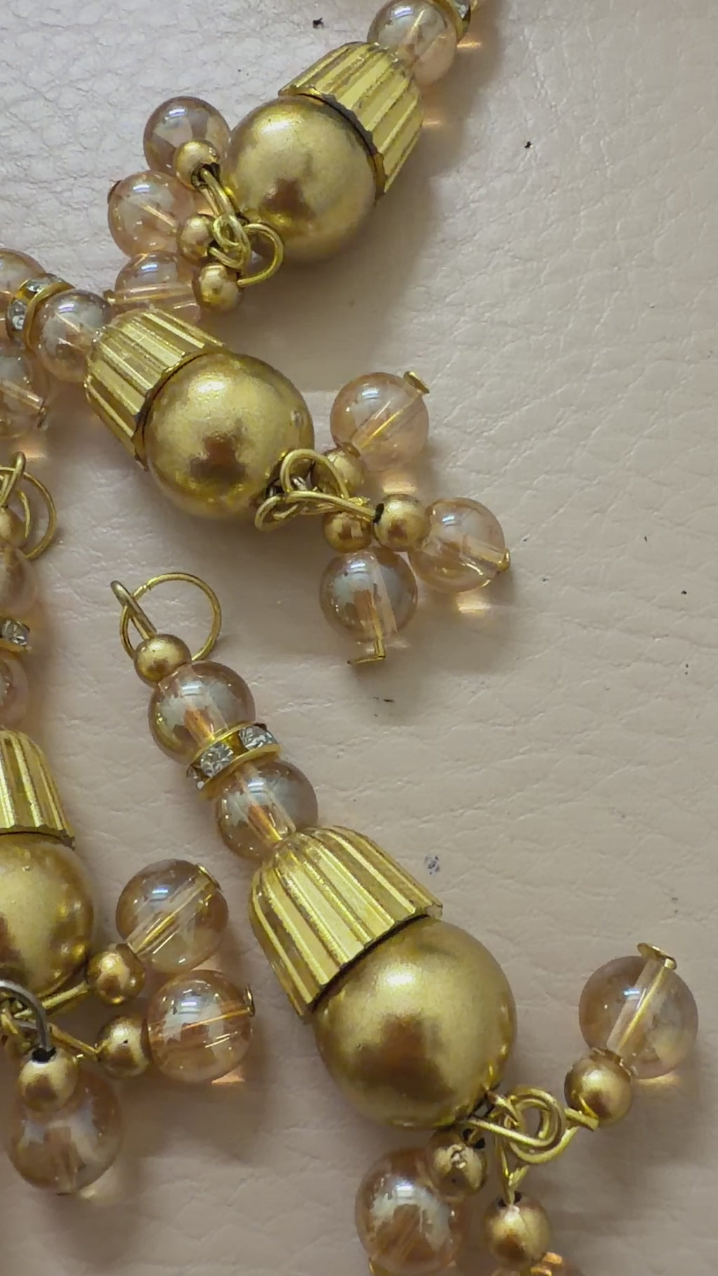 Gold and pearl beaded charms arranged in a grid on a beige background