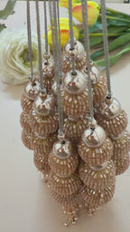 Pair of gold beaded tassel earrings on a light gray background