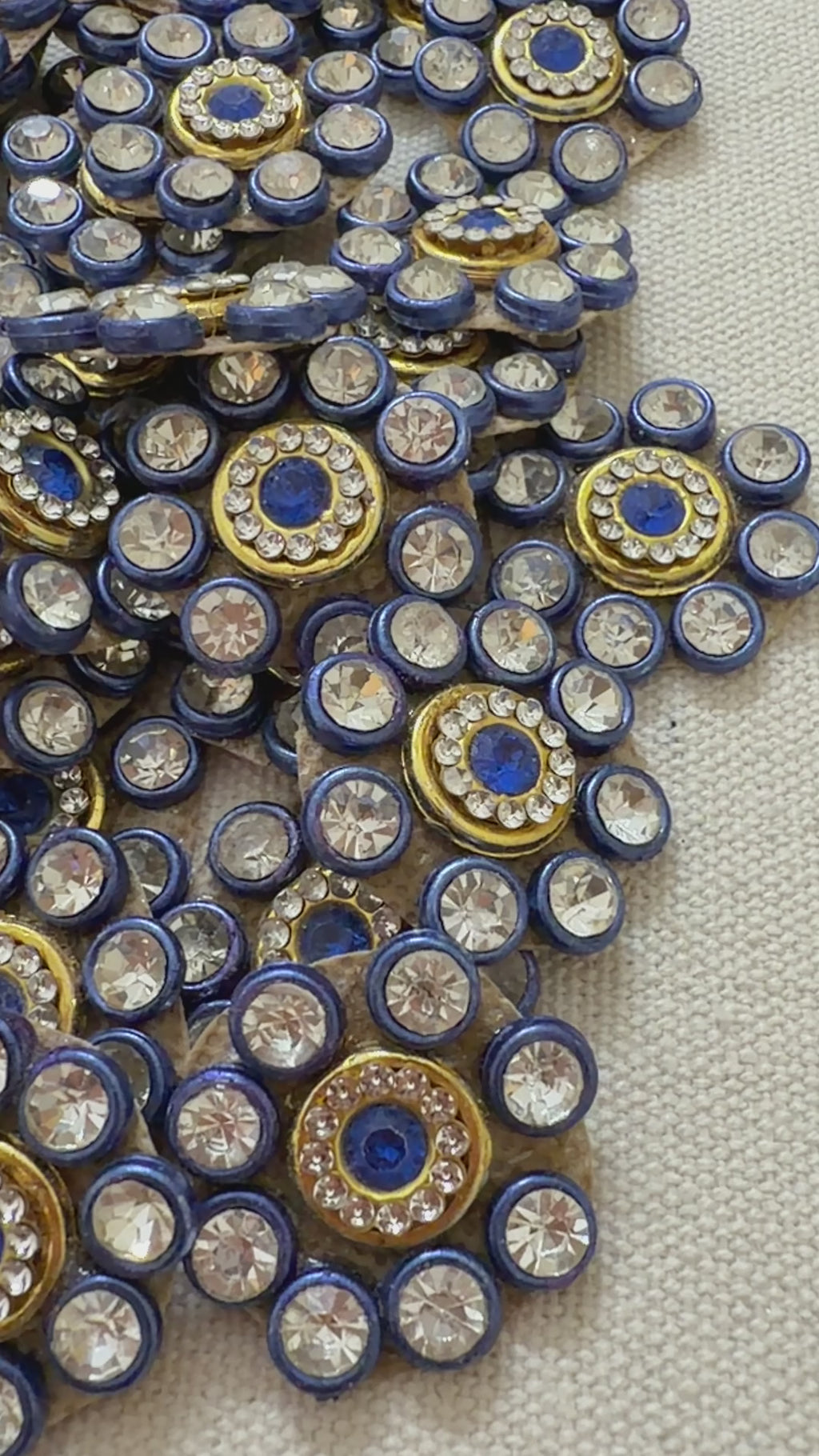 Close-up of decorative embellishments with blue centers and gold and silver accents on a neutral background.