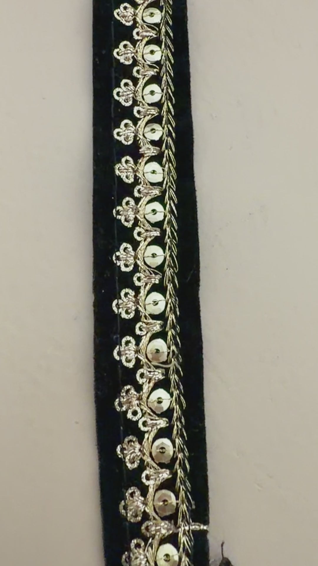 Black clutch with gold embroidery next to a white flower on a beige background