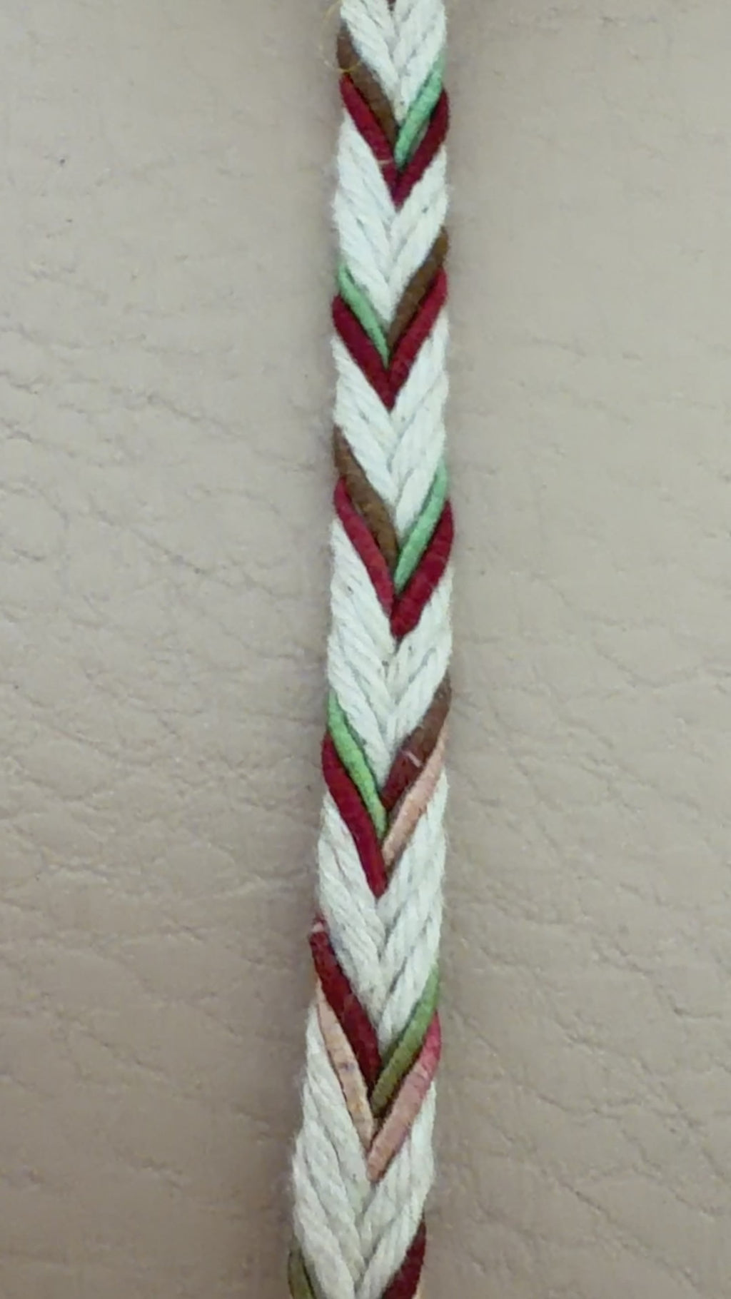 Spool of multicolored braided cable on a beige background