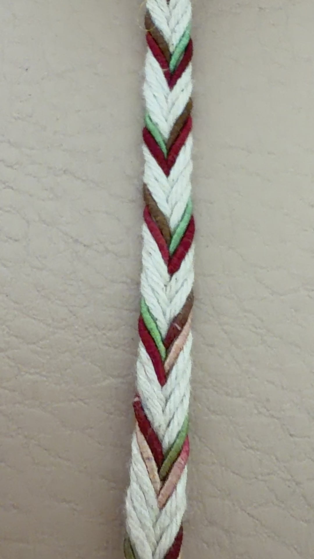 Spool of multicolored braided cable on a beige background