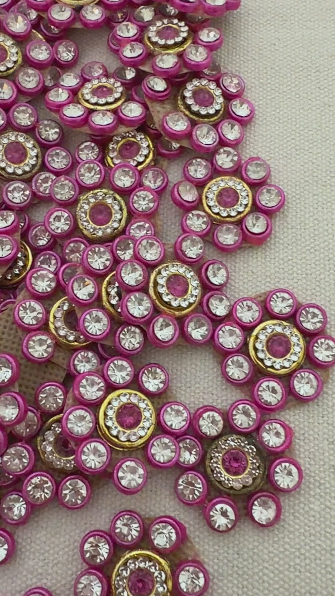 Decorative button with pink and gold accents next to a ruler on a textured surface