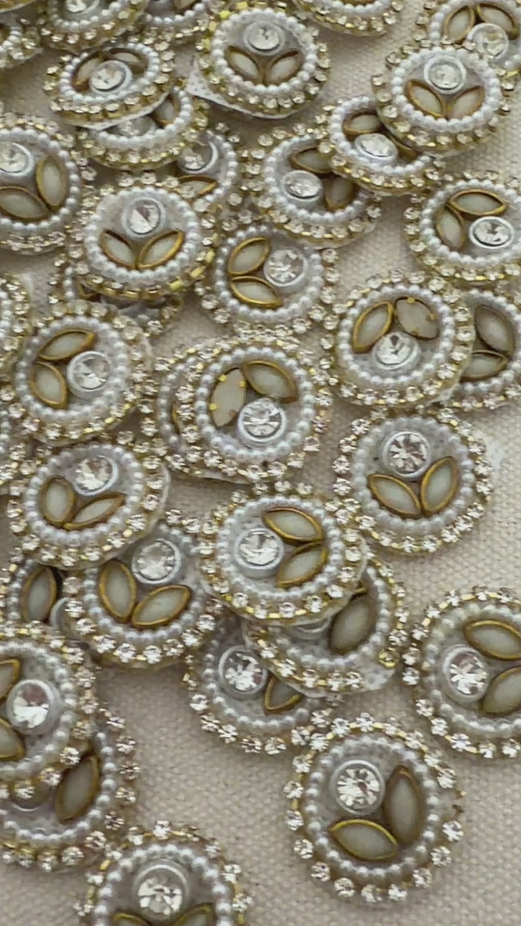 Close-up of decorative buttons with pearls and crystals on a beige fabric background