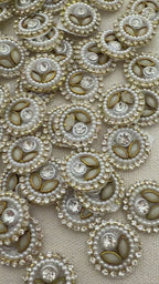 Close-up of decorative buttons with pearls and crystals on a beige fabric background
