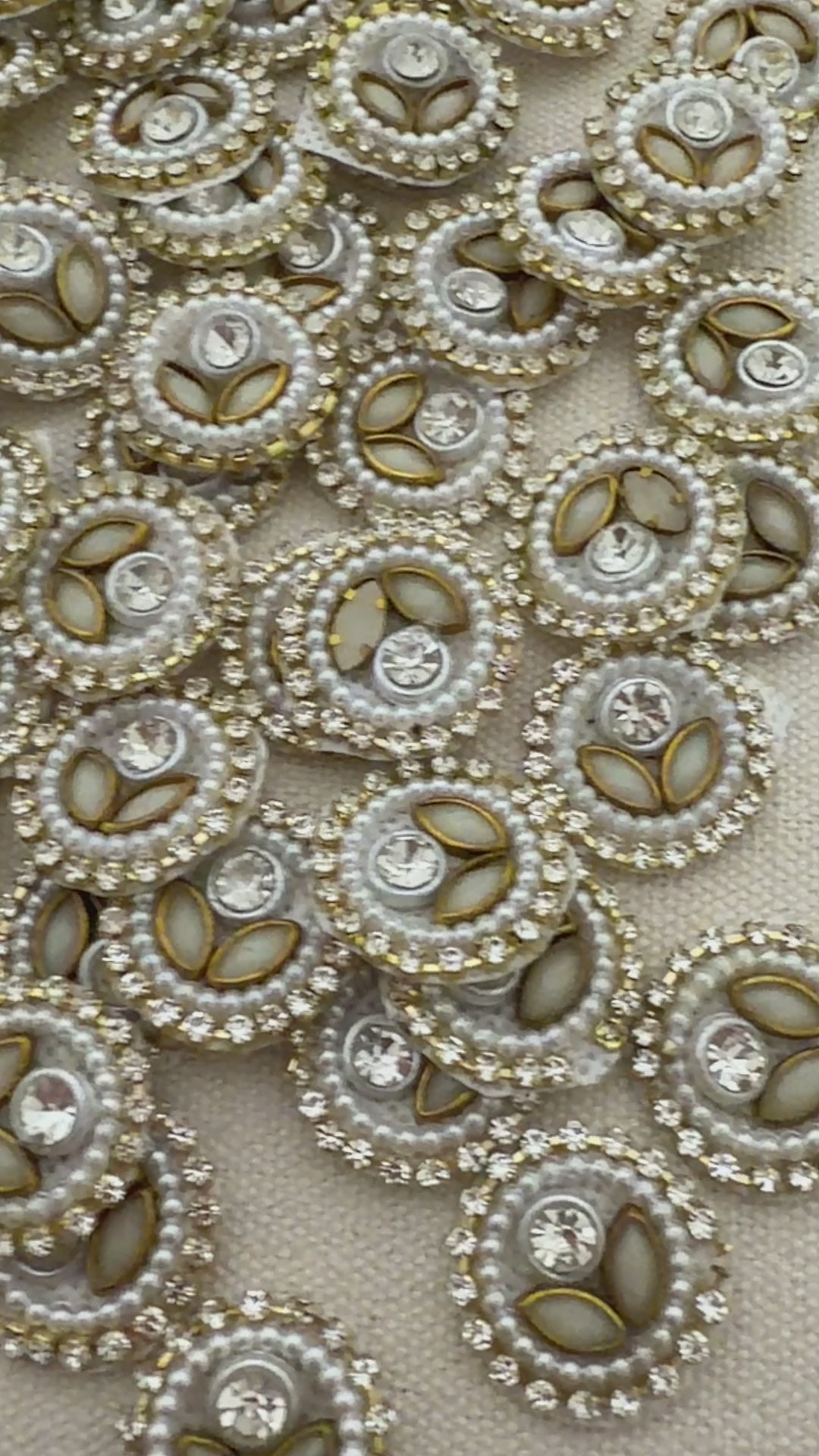 Close-up of decorative buttons with pearls and crystals on a beige fabric background