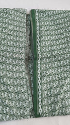 Textile with a pattern of small white shapes on a gray background, bordered by green and white geometric design.