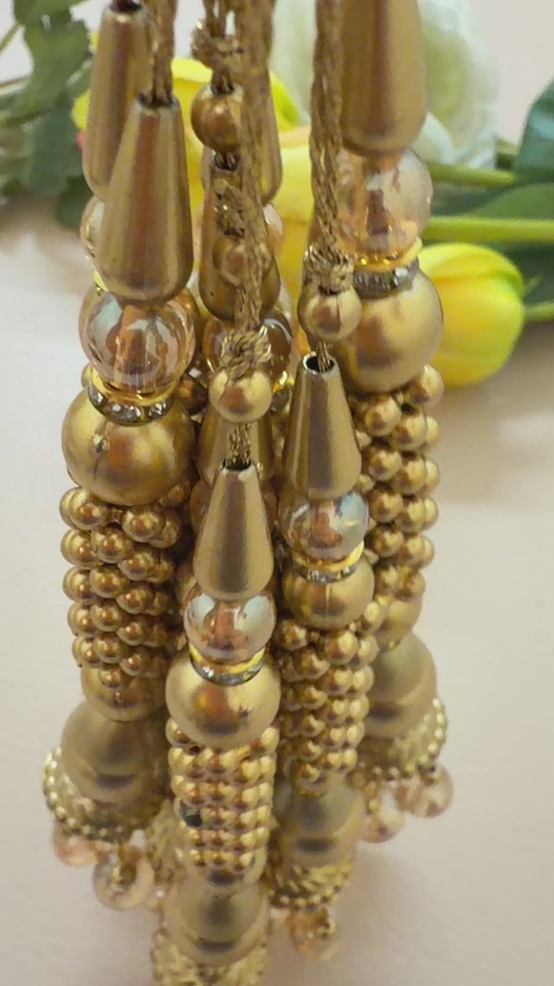 Gold earrings with beads on a light beige background