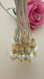 Set of pearl and gold beaded hair accessories with a pink rose on a beige background
