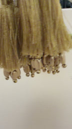 Gold tassels with beads on a light gray background
