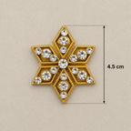 Decorative gold and crystal star-shaped brooch with measurements on a beige background