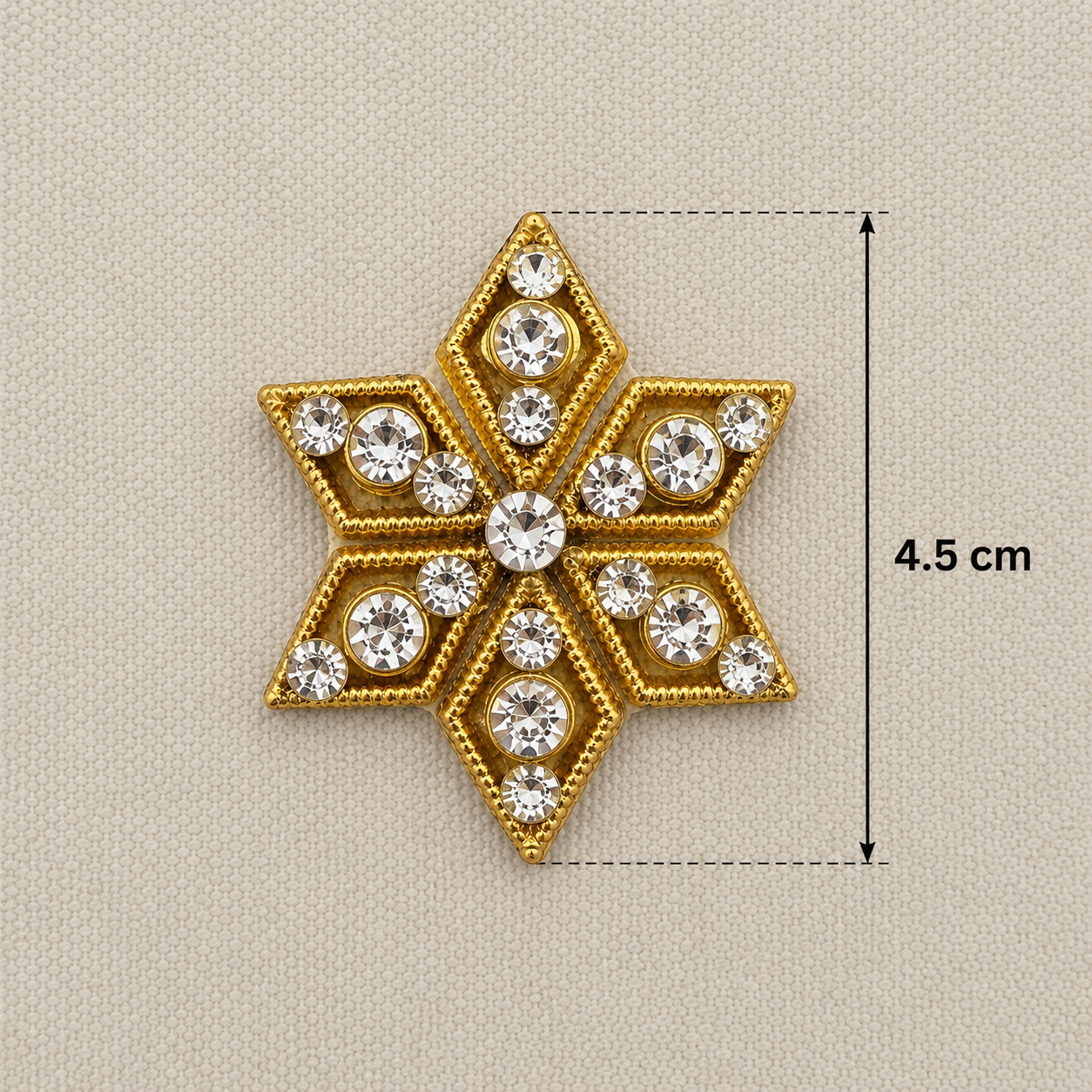 Decorative gold and crystal star-shaped brooch with measurements on a beige background